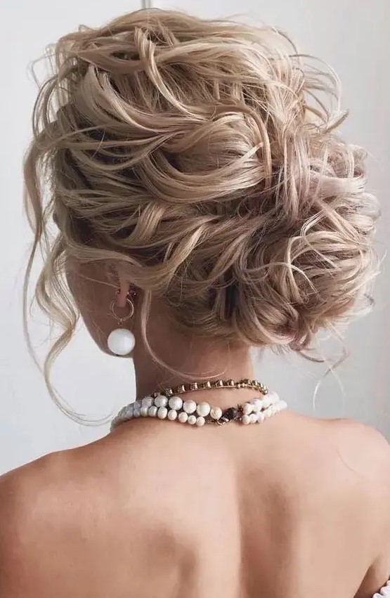 a beautiful and messy wavy wedding low bun with a wavy top, some locks down is a gorgeous idea for long hair