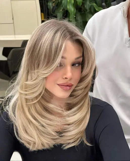 a beautiful blonde butterfly haircut with a darker root, a lot of volume and wavy ends is a stunning idea