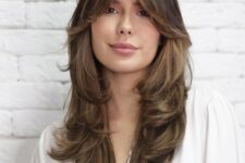 a beautiful long brown butterfly haircut with bottleneck bangs and caramel balayage plus curled ends is adorable