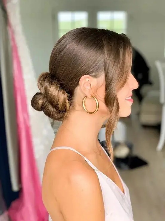 a beautiful twisted low bun with a sleek top and some wavy locks framing the face is a cool and chic idea to rock