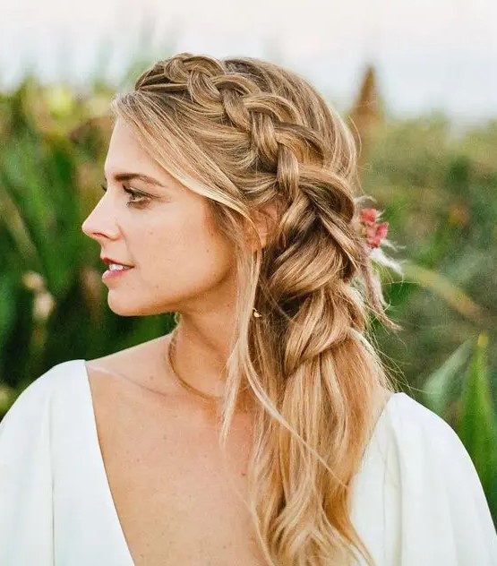A beautiufl and romantic side braid into a ponytail, with face framing waves is a stylish idea, accent it with fresh blooms