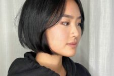 a black blunt chin-length bob with face-framing layers and a sleek finish is a cool and stylish solution for fine hair