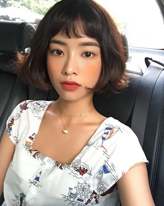 a black jaw-length wavy bob with wispy bangs is a catchy idea, it looks very girlish and relaxed