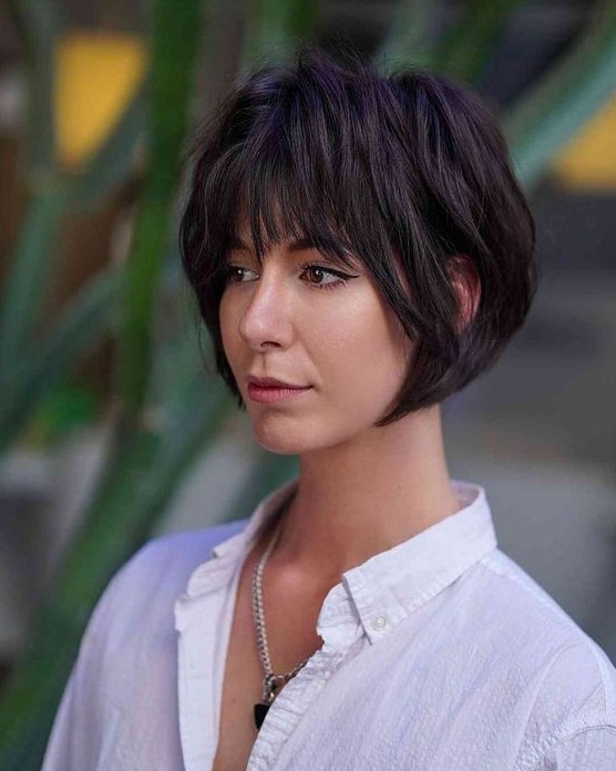 A black layered jaw length bob with wispy bangs and shaggy layers looks very retro inspired