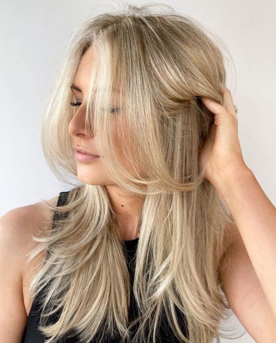 a bleached blonde butterfly haircut with curled ends and a bit of volume is a stylish idea for a anyone