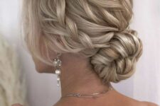 a blonde low bun with a braided halo and a braided top, face-framing locks is a chic and stylish idea
