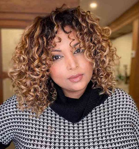 a bronde curly medium-length bob with a darker root is layered internally to maximize your curls