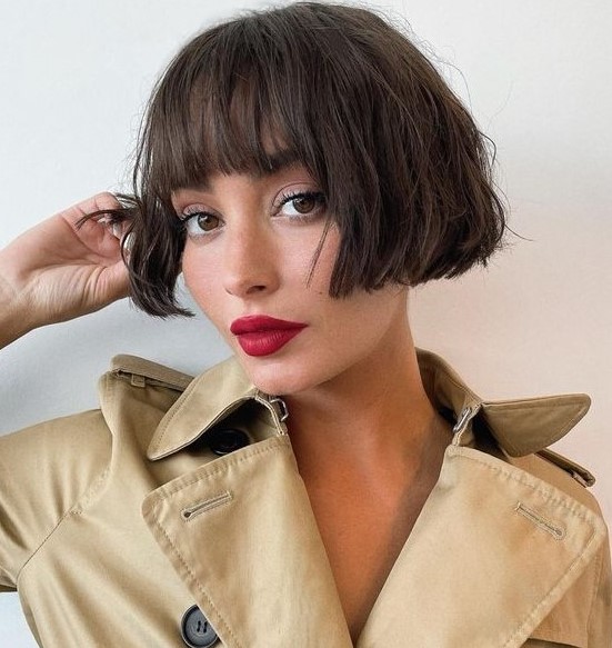 a chic dark brunette ear length bob with a classic fringe and messy waves looks relaxed, cute and refined