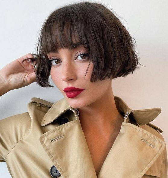 a chic dark brunette ear length bob with a classic fringe and messy waves looks relaxed, cute and refined