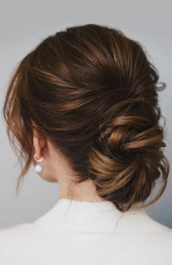 a chic low ballerina bun with a bump on top and face framing locks is a cool idea for a wedding