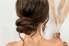 a chic twisted low bun with a bump on top and some waves down is a lovely wedding hairstyle for long and thick hair