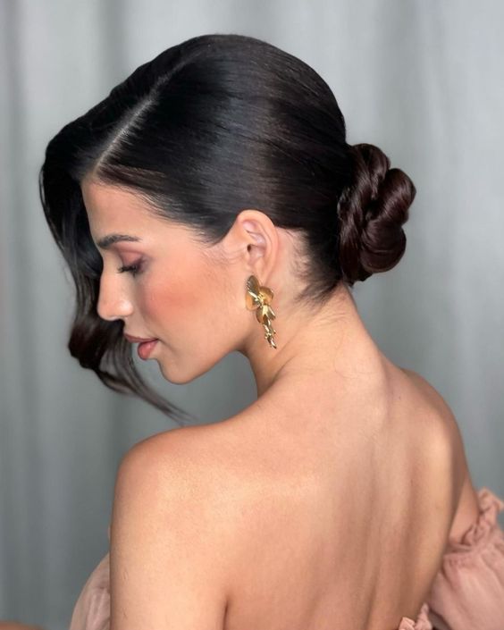 a classy wrapped low bun, a sleek top and waves framing the face on one side only create a very elegant sophisticated look