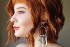a copper red shaggy wavy bob with a classic fringe and a bit of volume is a bold and chic idea