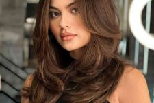 a dark brunette butterfly haircut on long hair, with waves and volume is a stylish and catchy idea