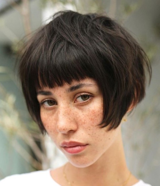 a dark brunette ear length bob with a classic fringe and a messy volume is a cool solution and this hair is easy to style