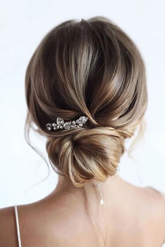 a dimensional low bun with a volumious top and a loose bun plus a rhinestone hairpin is lovely