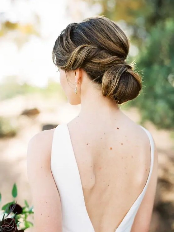 a formal and elegant low bun with a bump on top and waves around the face is a chic and cool idea