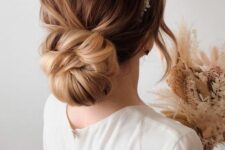 a large twisted low bun with a messy top and a bead and pearl headpiece is a gorgeous idea for a refined bride
