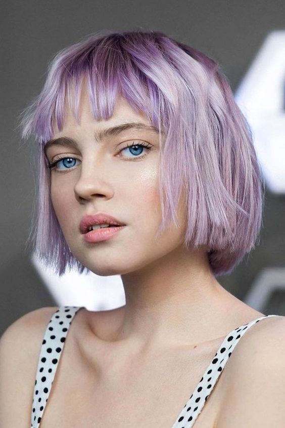 A lilac jaw length bob with wispy bangs and a bit of texture is a relaxed hairstyle with a catchy color