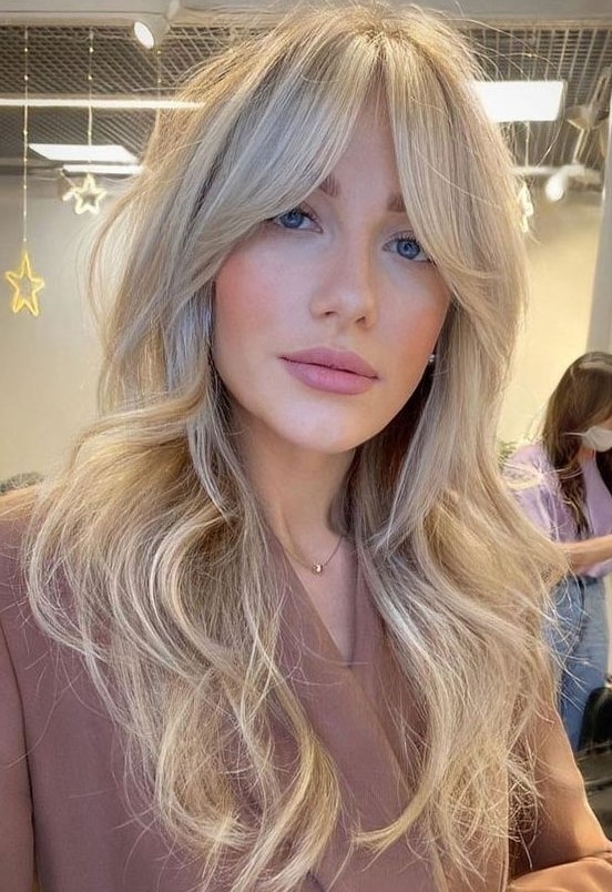 a long blonde butterfly haircut with curtain bangs and waves is a very lovely and delicate idea