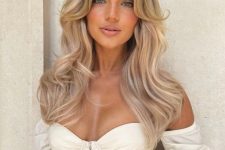 a long blonde butterfly haircut with wavy ends and some volume plus perfect curtain bangs