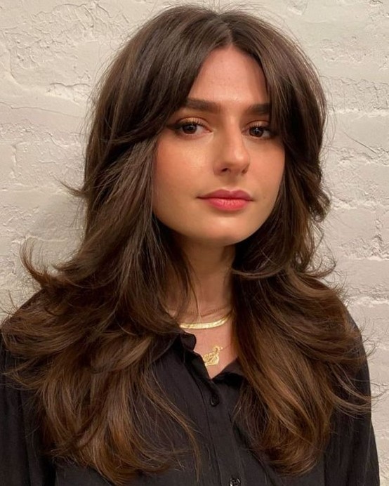 a long brown butterfly haircut with curled ends and short curtain bangs is a chic and lovely idea