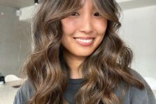 a long brunette butterfly haircut with caramel and bronde balayage with bottleneck bangs and waves is a chic idea