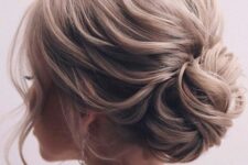 a loose low bun of wavy hair, wiht a wavy and voluminous top and face-framing is a cool idea for an elegant bride