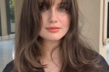 a lovely brunette butterfly haircut with waves and wispy bangs is a cool and chic idea and it shows off your locks