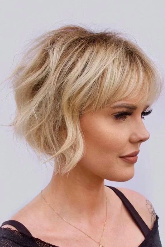 a lovely ear length blonde bob with a classic fringe and messy waves plus a lot of volume is very chic