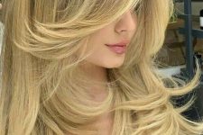 a lovely golden blonde butterfly haircut with wavy ends and a lot of volume is a catchy and chic idea