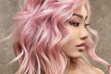 a lovely light pink outgrown bob with messy and textured waves and a lot of volume looks adorable