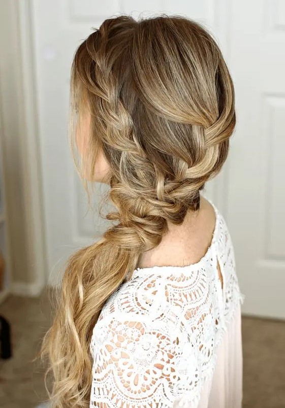 a lovely side swept braid into a ponytail, with a bump on top and waves down is a great idea for a boho or rustic bride