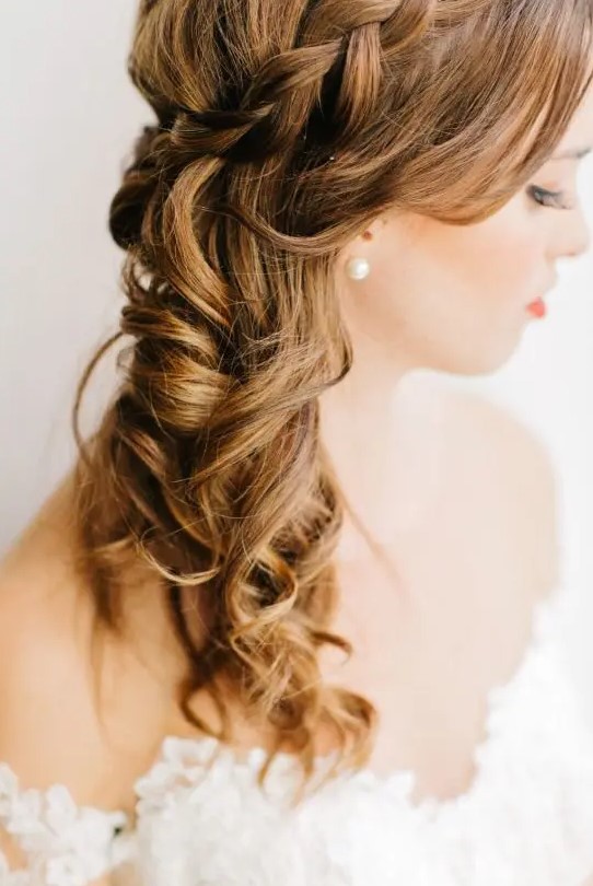 A lovely side swept half updo with a braided halo and waves down and face framing locks is adorable