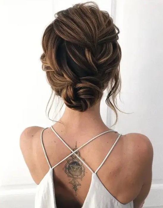 a lovely twisted wedding low bun with a braided twisted top and some locks framing the face is a chic and cool idea