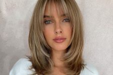 a medium-length blonde butterfly haircut with wispy bangs and curved ends is a delicate and girlish solution