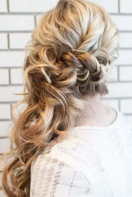 a messy and voluminous wavy side swept ponytail with a bump on top is a catchy and chic idea for a bride