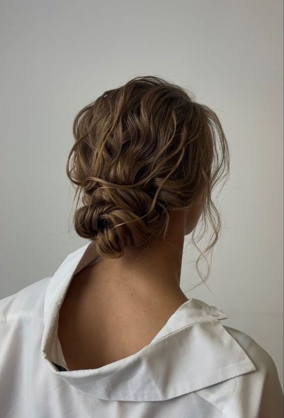 a messy elegant low bun with a wavy top and a wavy twisted bun, some locks down is a cool idea