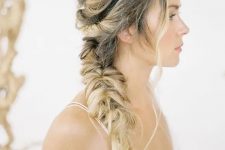 a messy side swept hairstyle with a messy volume on top and a braid on one side plus waves down is a chic and cool idea