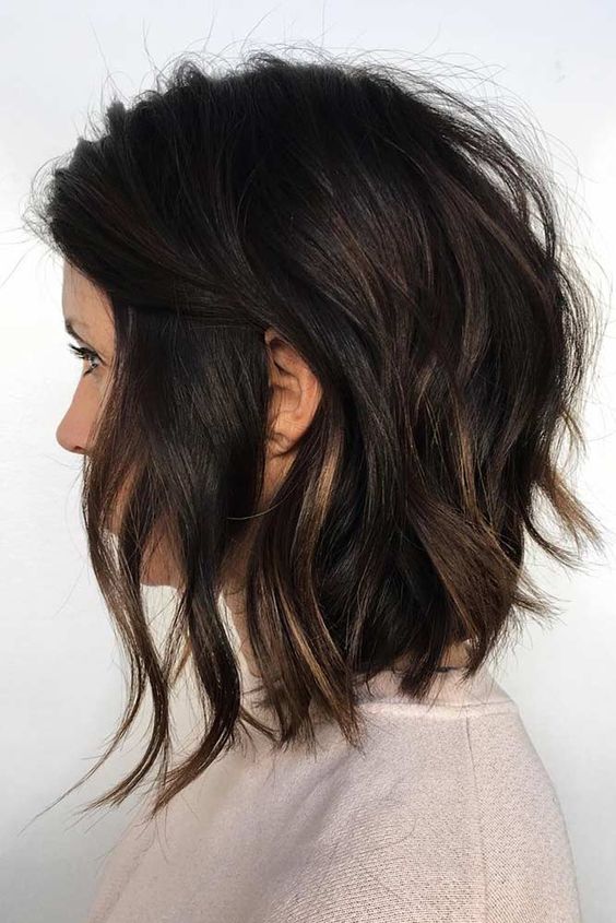 a messy wavy black bob with slight honey blonde balayage is a bold and catchy idea, lots of volume and dimension makes the look wow
