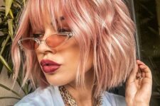 a pink midi length bob with outgrown wispy bangs and waves is a cool and chic idea