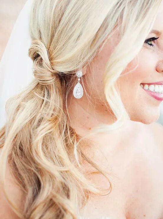a pretty and easy blonde knot side ponytail and waves framing the face are a simple and cool idea for a wedding