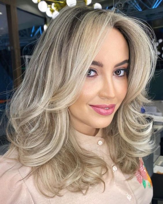 A pretty blonde medium length butterfly haircut with wavy ends and a lot of volume is a lovely idea, and this cold shade of blonde is chic