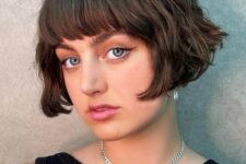 a short brunette bob with a classic fringe and messy waves is a retro-inspired and chic hairstyle
