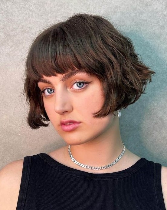 a short brunette bob with a classic fringe and messy waves is a retro inspired and chic hairstyle