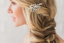a side swept loose twisted braid with a bump on top and an embellished hair piece is a chic and stylish idea for a bride