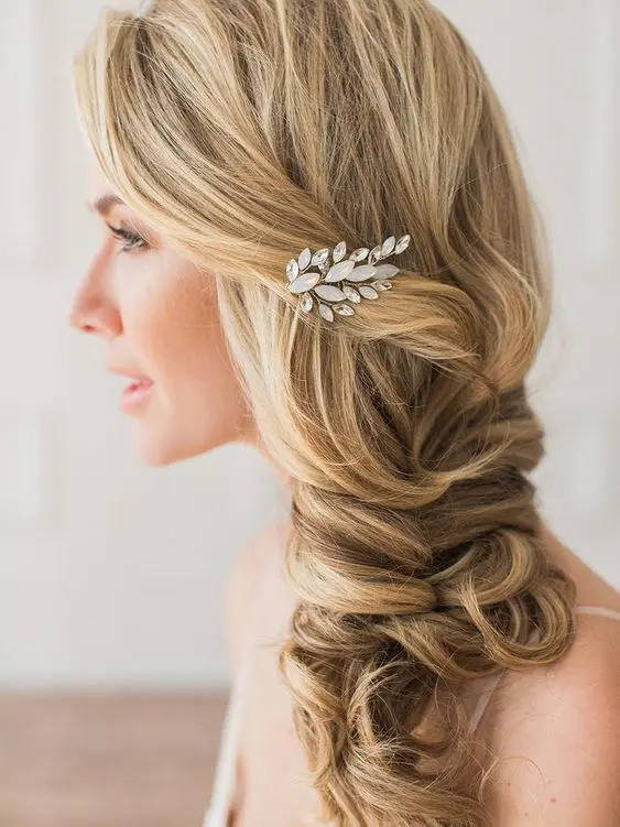 a side swept loose twisted braid with a bump on top and an embellished hair piece is a chic and stylish idea for a bride