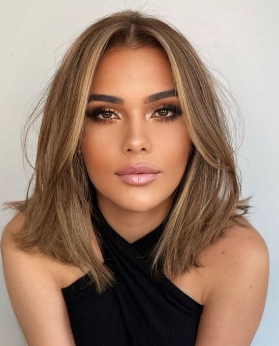 a soft bronde outgrown bob with a bit of blonde highlights and soft curtain bangs dyed blonde, too