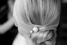 a super sleek low bun hairstyle with no bumps is spruced up with large pearl pins for a chic look