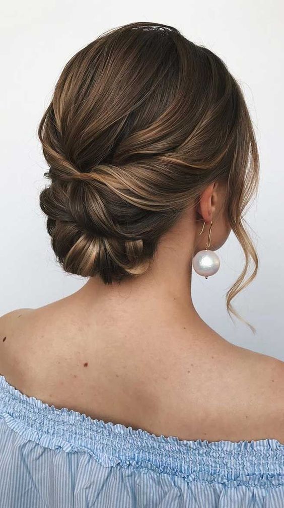 a twisted low bun with a bump on top and some face framing waves is a cool idea for a bride
